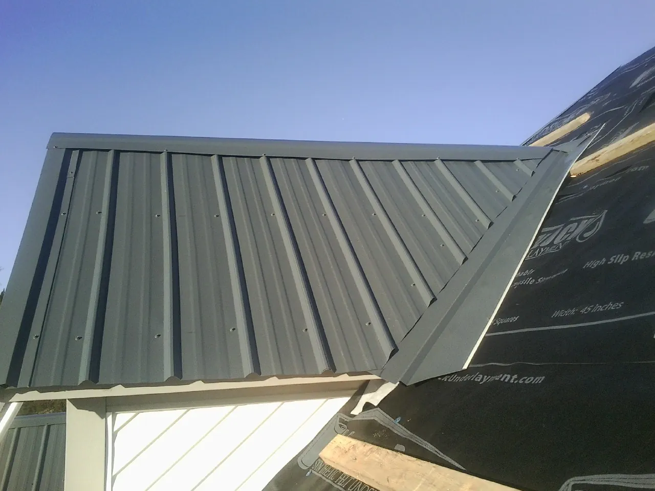 Gray metal roof panels going on over a garage gable in Wilson