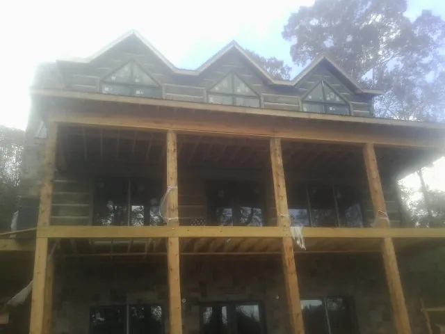 Dormers and porch framing on a large log home under construction — Roof Coating work by our crew in Wilson
