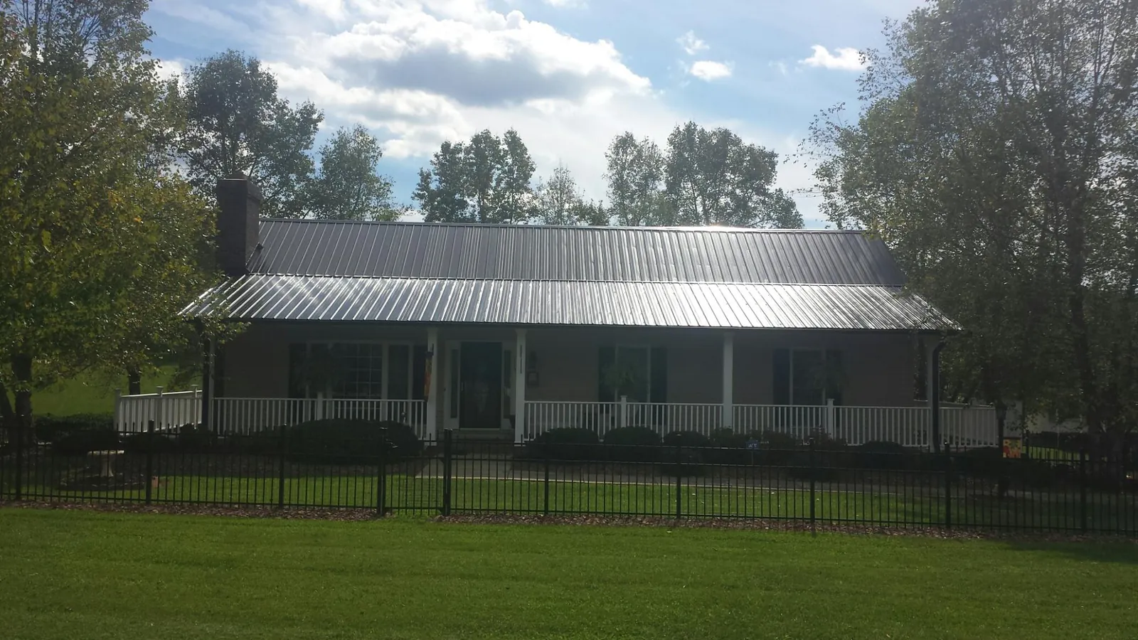 Gray metal roof on a brick ranch with a full width front porch — Gutter Guard Installation work by our crew in Wilson