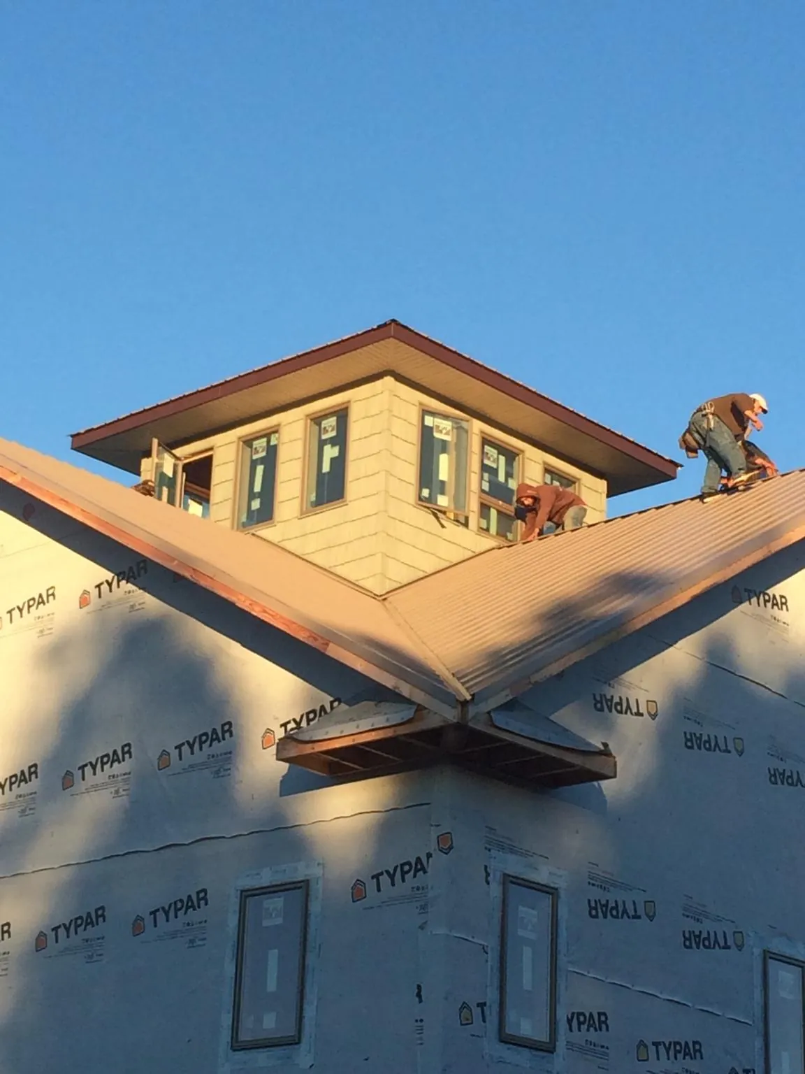 Roofers working around a rooftop cupola on a new metal roof at sunset — Roof Waterproofing in Wilson by Roofing Brothers